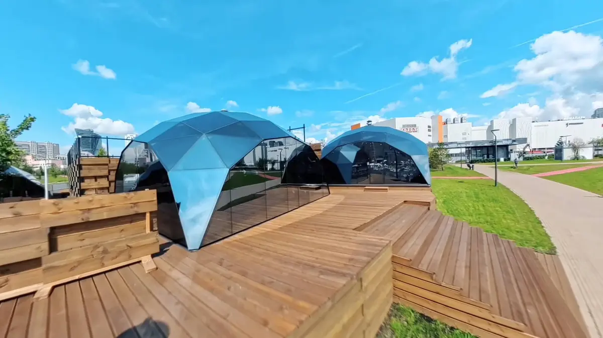 Купола AuraSPA в парке Ходынское поле, за ними — ТРЦ «Авиапарк»